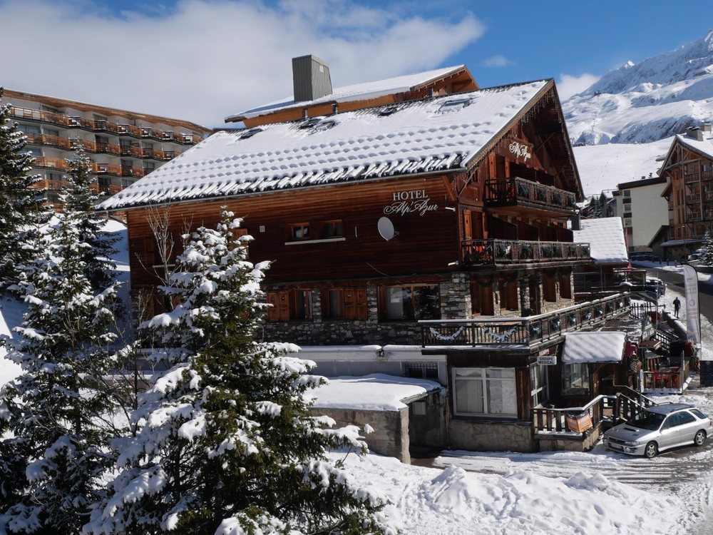 Le chalet de l'Hôtel Alp'Azur sous la neige, ses balcons de bois et les sapins enneigés devant