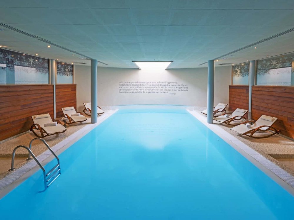 La piscine intérieure chauffée du spa Nuxe d'Au Chamois d'Or, son puits de lumière et ses transats