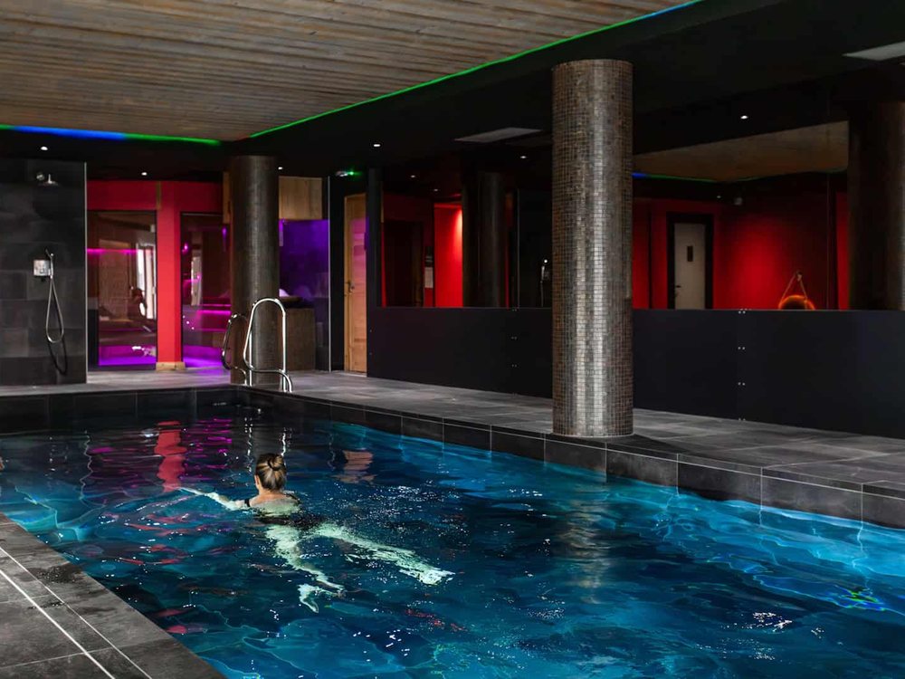 La piscine intérieure chauffée du spa de Daria-I Nor, sa lumière bleue et ses piliers de pierre sombre