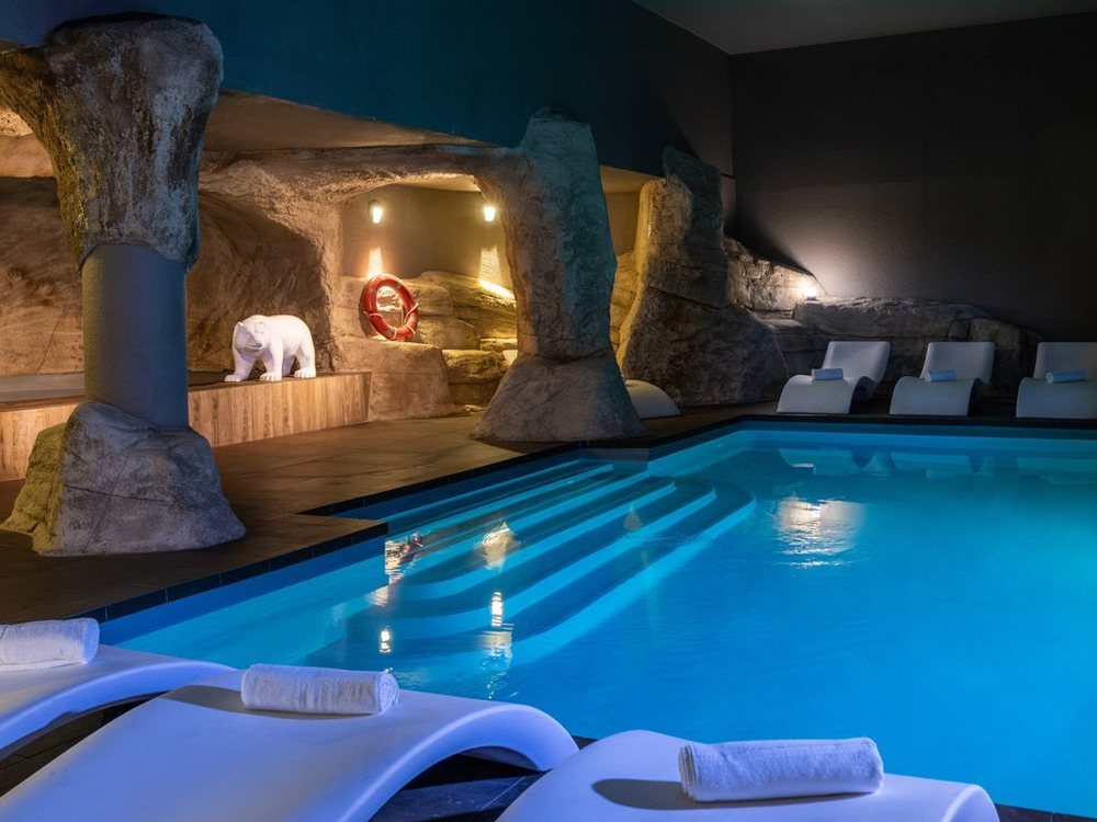 La piscine intérieure de la Grotte de l'Ours au Royal Ours Blanc, ses parois de roche et ses transats