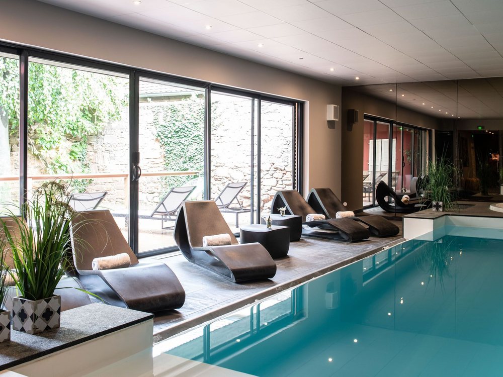 La piscine intérieure à débordement du Chambard, ses transats alignés le long de la baie vitrée ouverte sur la terrasse