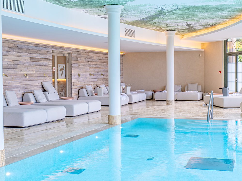 La piscine intérieure des Violettes, ses colonnes blanches, son plafond peint et ses lits de repos