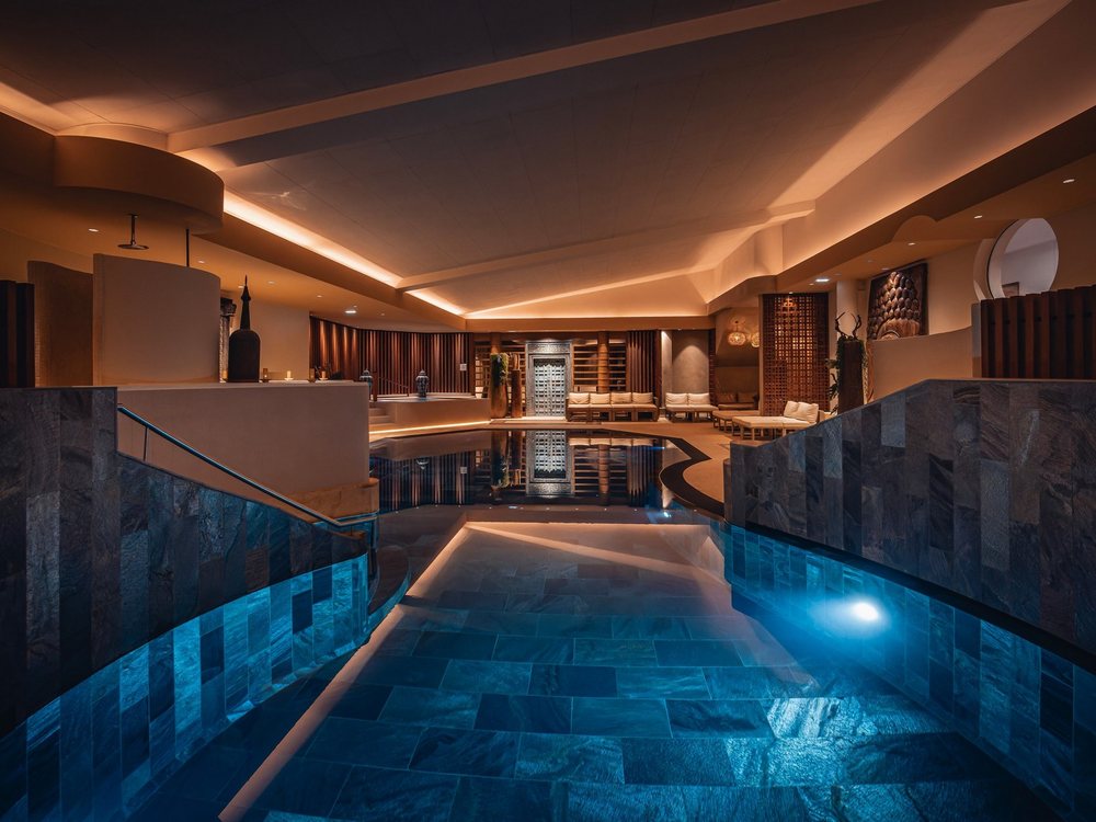 La piscine de pierre noire du Yonasaya, à YONA, bordée d'alcôves éclairées et de murs de pierre