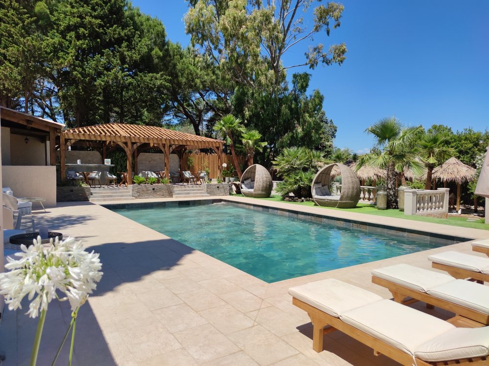 La piscine chauffée de La Villa Dune, ses transats et ses paillotes, dans le golfe de Saint-Tropez