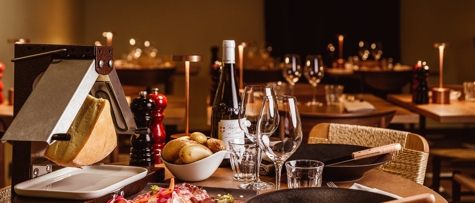 Une raclette servie à La Laiterie de l'Altapura, fromage, charcuterie, pommes de terre et verres de vin