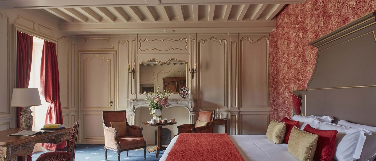 Une suite du Château d'Audrieu, plafond à la française, boiseries claires, cheminée de marbre et tenture rouge