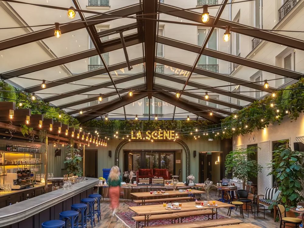 La guinguette du Chouchou Hôtel sous sa verrière, ses guirlandes lumineuses, sa scène et ses longues tables