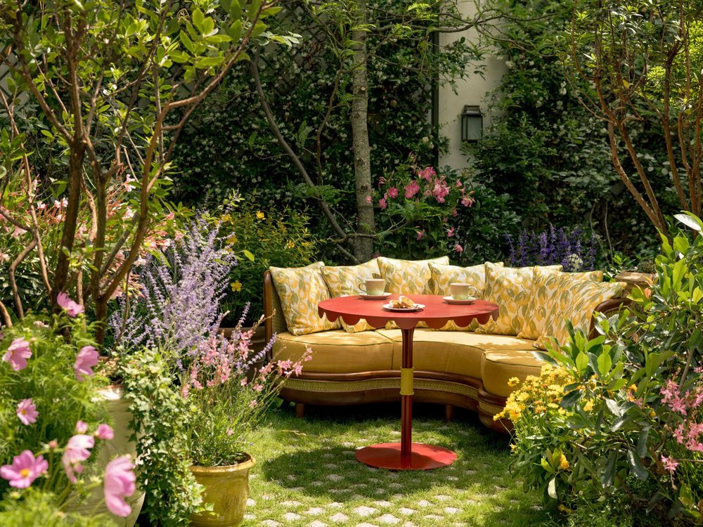 Le jardin de La Fantaisie, ses massifs fleuris, son banc arrondi jaune et sa table rouge sous les arbres