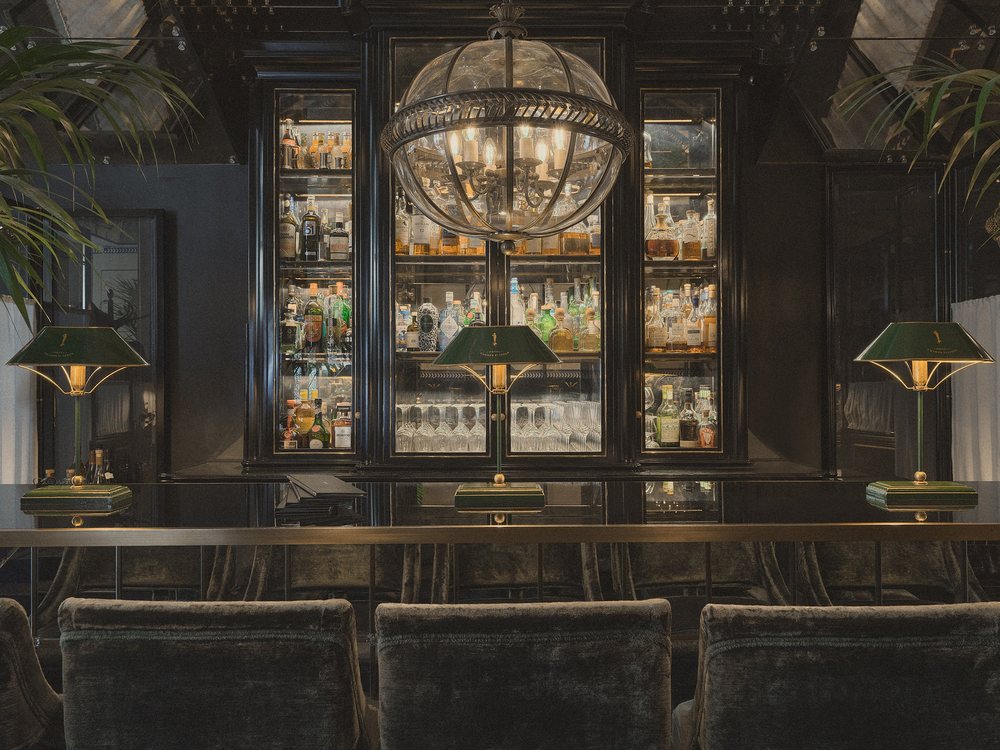 Le bar de Monsieur George, ses vitrines de bouteilles, son lustre en verre et ses lampes vertes