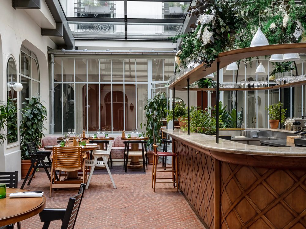 Le restaurant des Grands Boulevards sous sa verrière, ses plantes, son bar en bois tressé et ses tables
