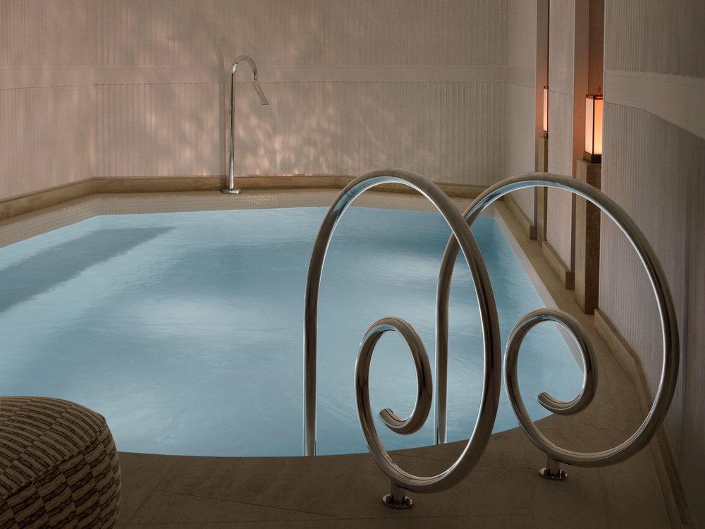 Le bassin de nage de l'Hôtel Hana et ses échelles de métal en volutes, sous une lumière douce