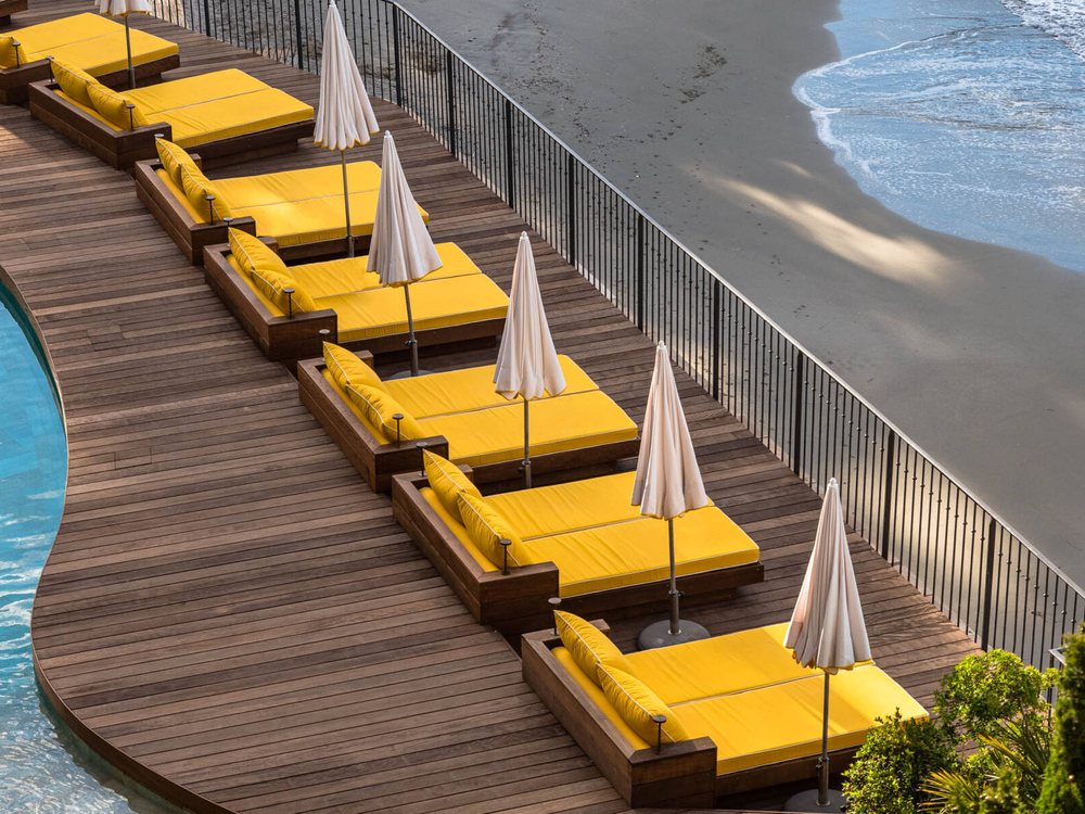La piscine du Bailli de Suffren et ses transats jaunes au-dessus de la plage privée et de la mer