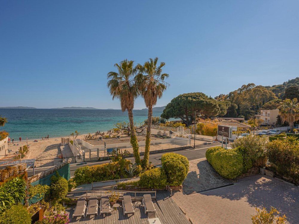 Le Grand Pavois et sa terrasse au-dessus de la plage d'Aiguebelle, palmiers et mer sous le soleil