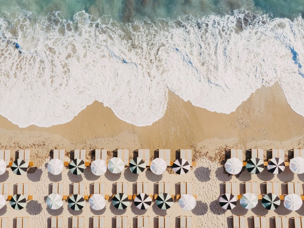Les parasols et les transats du Beach Club de Lily of the Valley alignés sur le sable de Gigaro, vus du ciel