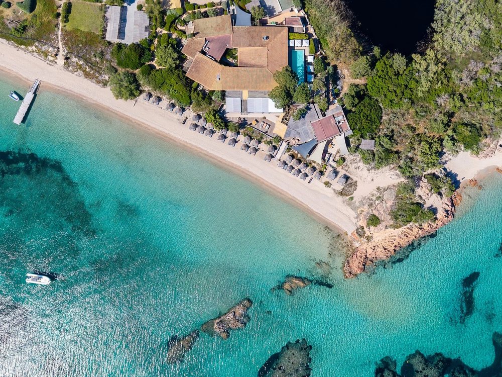 La Plage Casadelmar vue du ciel, son anse de sable, son ponton et l'eau turquoise de la presqu'île du Benedettu