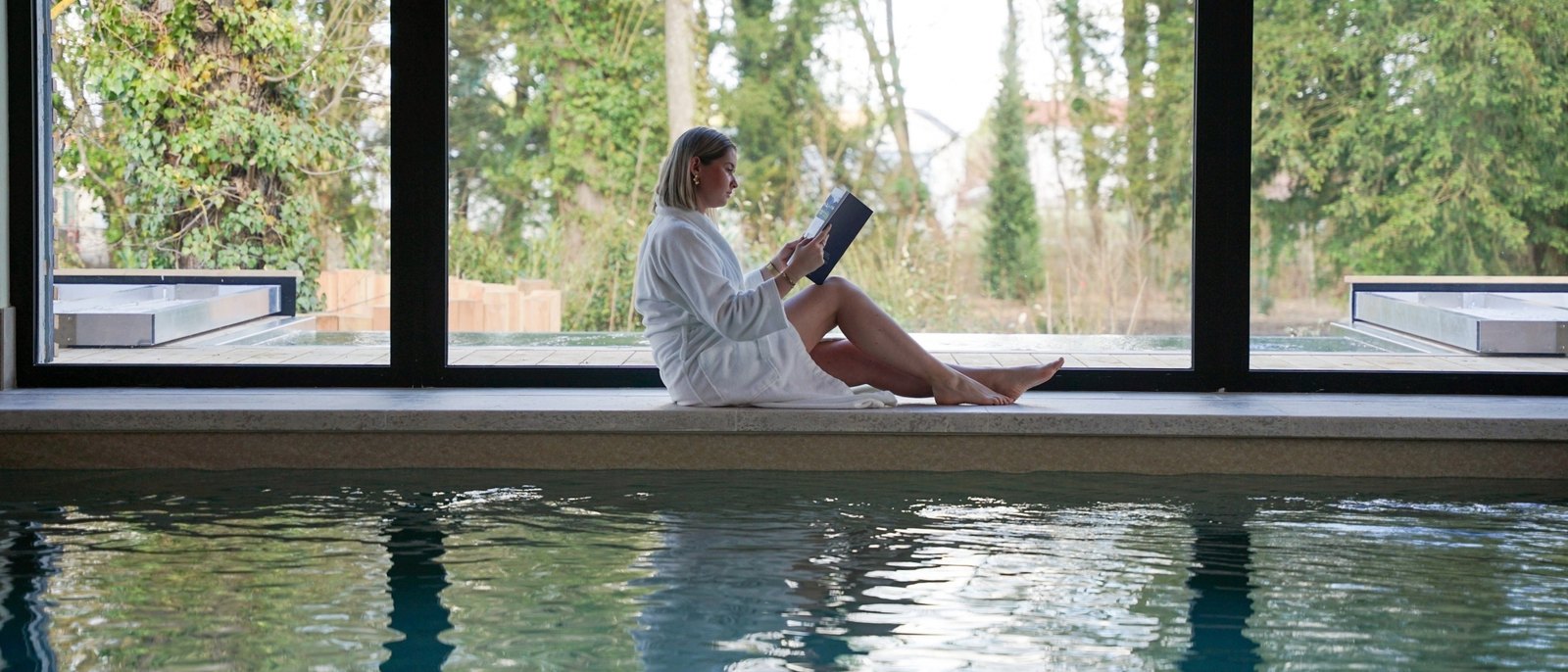 La piscine intérieure du Spa Sisley de l'Hostellerie de Levernois, grandes baies vitrées ouvertes sur le parc et bain à remous extérieur