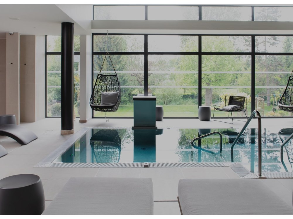 Le bassin de relaxation du vineaSpa du Richebourg, fauteuils suspendus et baies vitrées sur le jardin