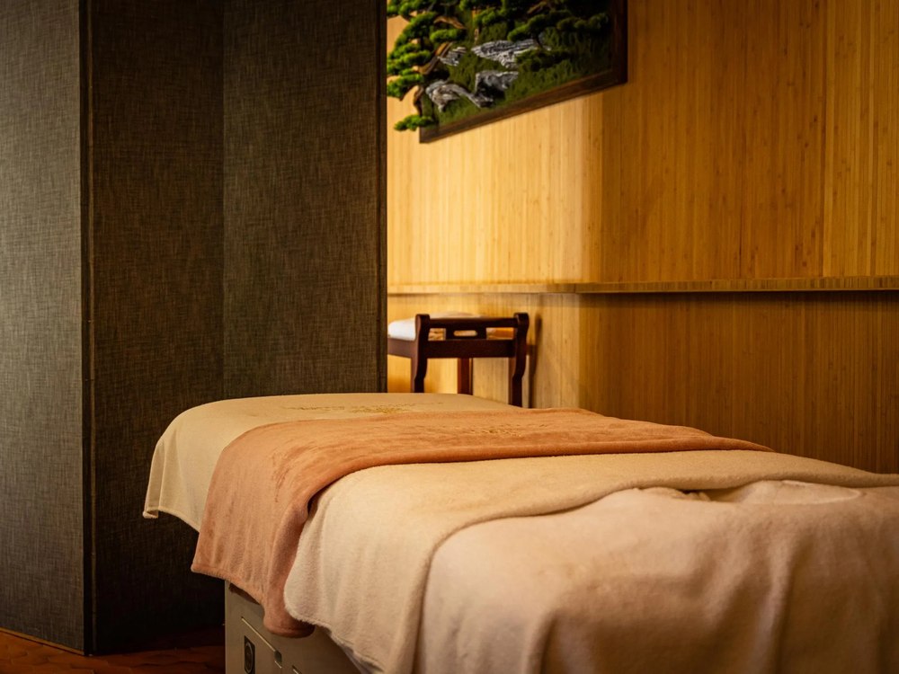 Une cabine de soins du Spa Marie de Bourgogne à l'Hôtel Le Cep, lambris de bambou et table de massage drapée