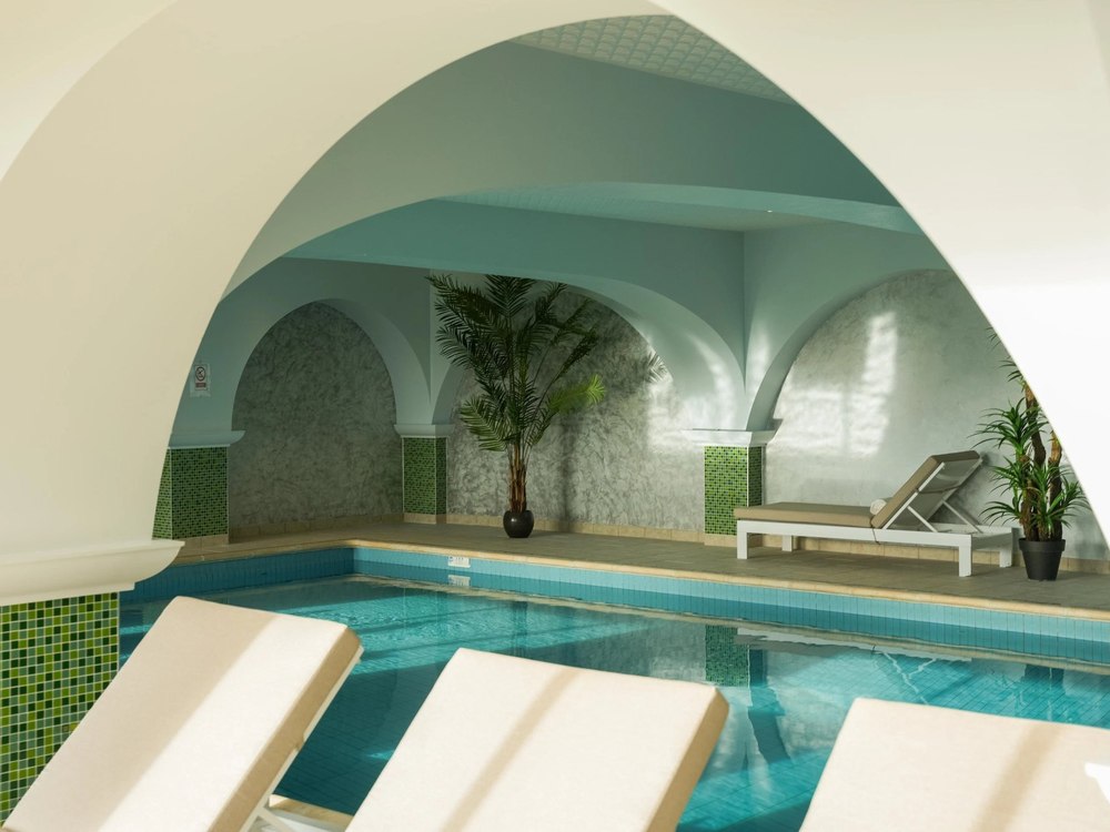 La piscine intérieure de La Côte Saint-Jacques à Joigny, bassin turquoise sous des voûtes blanches et mosaïque verte