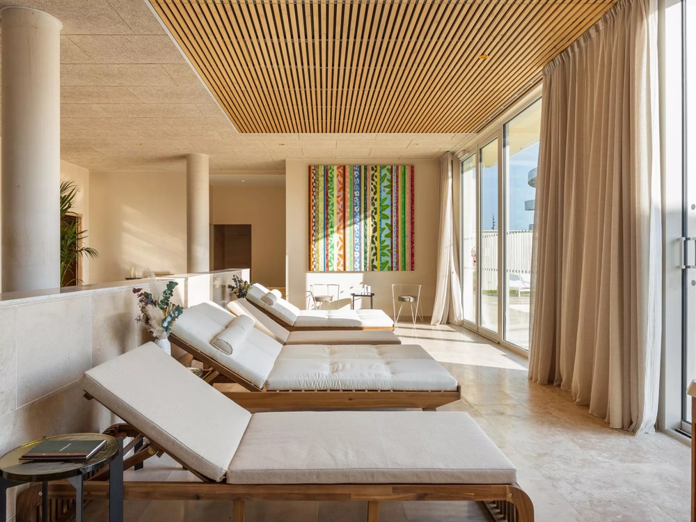 L'espace de repos du spa Gemology au voco Beaune, bains de soleil en teck sous un plafond à lames de bois et grande baie vitrée