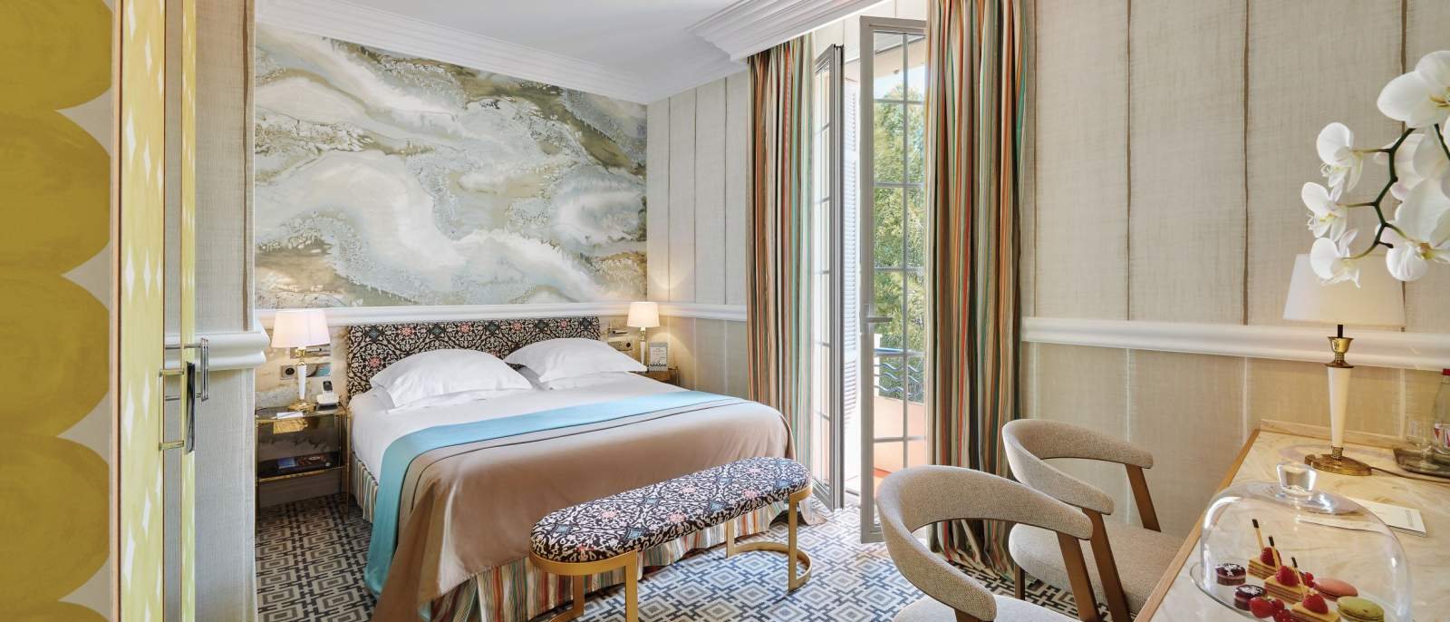 Une chambre supérieure du Belles Rives, son décor Art déco et sa porte-fenêtre ouverte sur le Cap d'Antibes