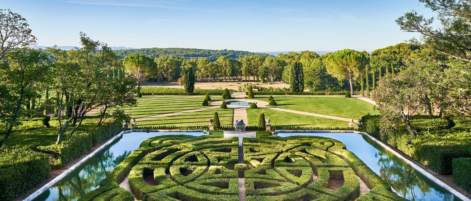 Le jardin à la française du Château de la Gaude, ses buis taillés en labyrinthe et ses bassins, face aux pins et à la campagne d'Aix-en-Provence