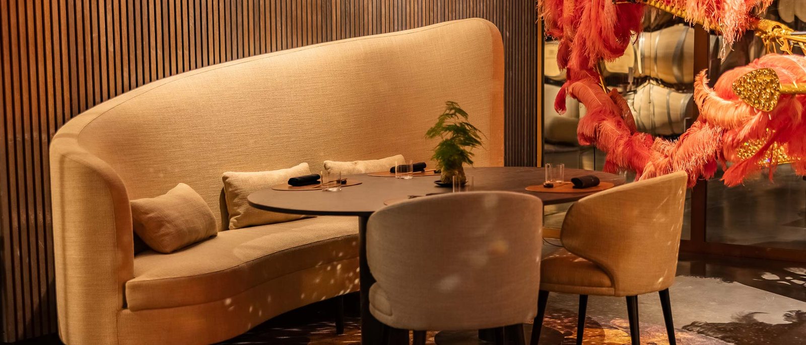 Une banquette arrondie du restaurant Le K, sous les plumes roses du Lilicoptère de Joana Vasconcelos