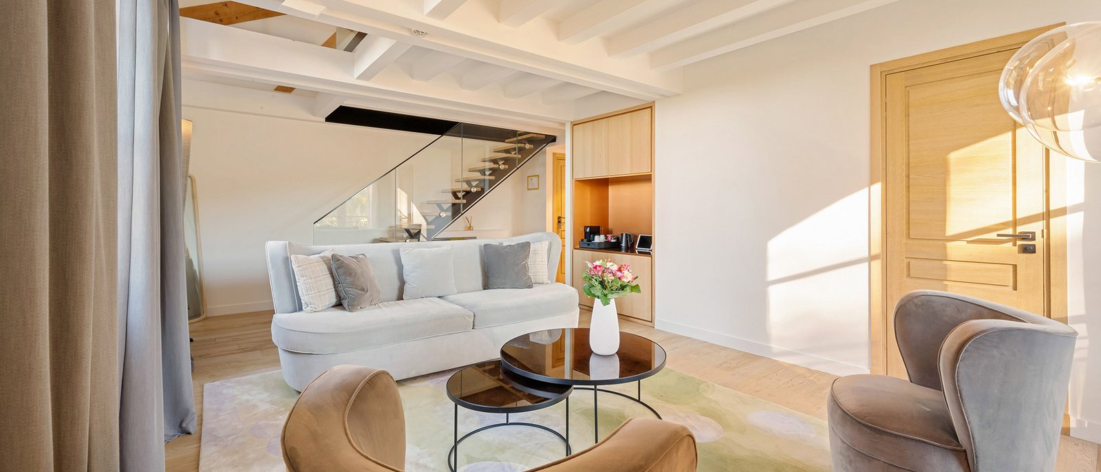 Le salon d'une suite en duplex du Château de la Gaude, canapé blanc, fauteuils et escalier vers la chambre