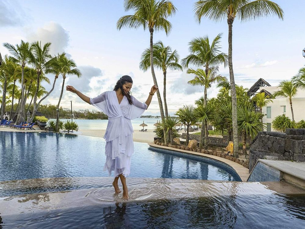 Une cliente marche sur le bord de la piscine à débordement du Shangri-La Le Touessrok, face au lagon