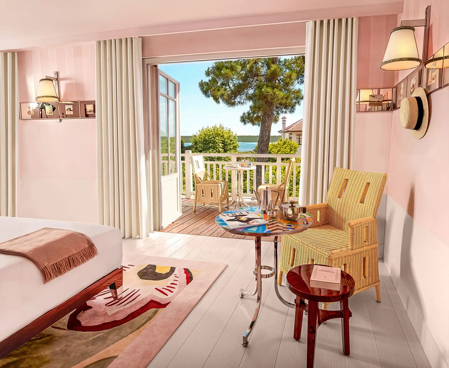 Une chambre rose poudré de la Villa Colette, au Cap-Ferret, ouverte sur un balcon et un pin maritime