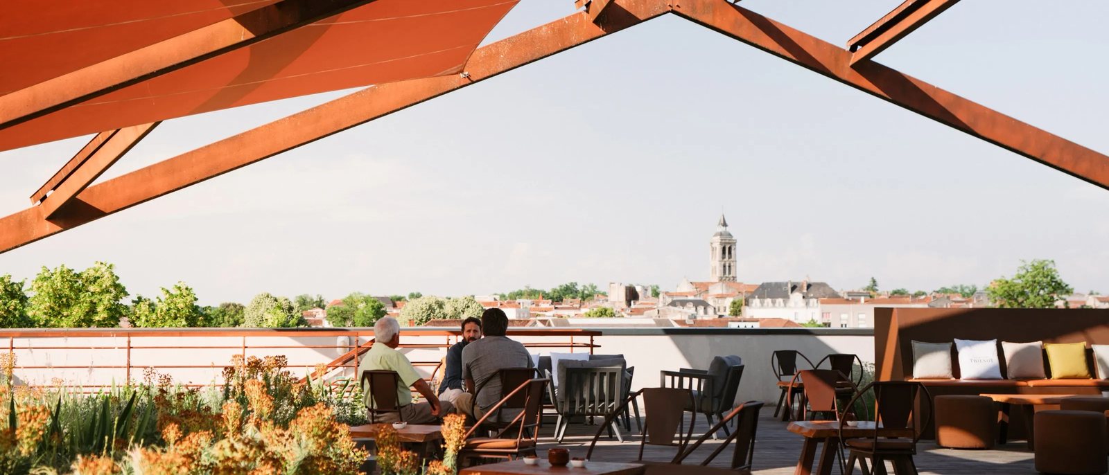 Le rooftop de l'Hôtel Chais Monnet sous sa structure d'acier rouille, face aux toits et au clocher de Cognac