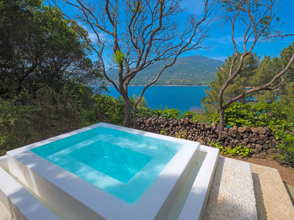 Un jacuzzi à débordement d'A'mare Corsica sous les arbres, face au golfe du Valinco et aux montagnes