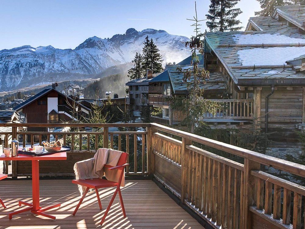 La terrasse d'une chambre de La Sivolière, ses chaises rouges face aux chalets et aux sommets enneigés