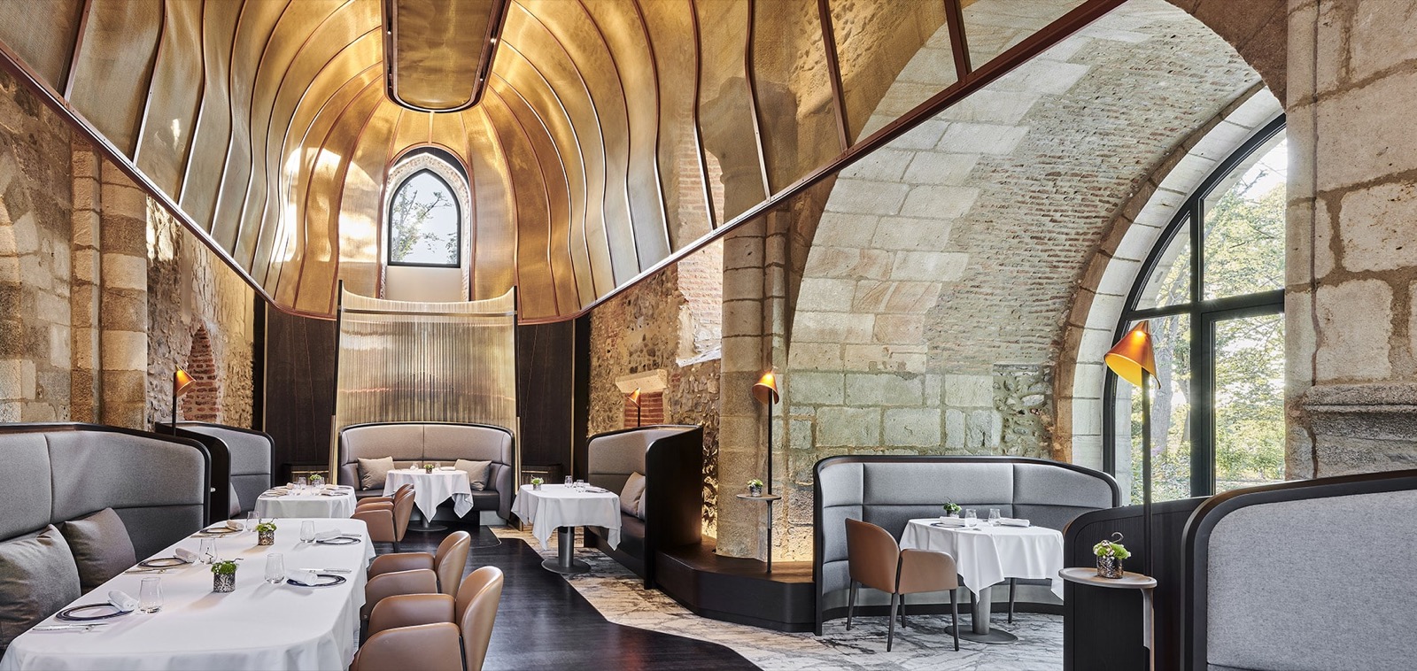 La salle du restaurant La Chapelle au Château Saint-Jean, dôme de cuivre doré sous la voûte romane et murs de pierre apparente