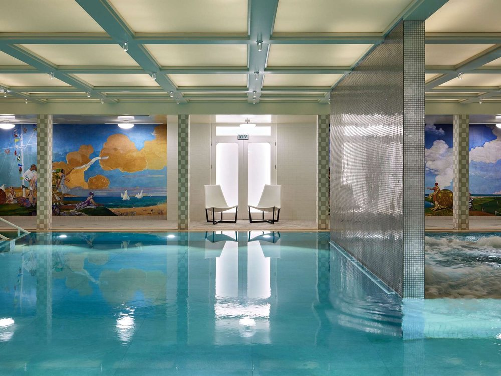 La piscine d'eau de mer des Cures Marines, sous un plafond à caissons, entre deux grandes fresques de bord de mer