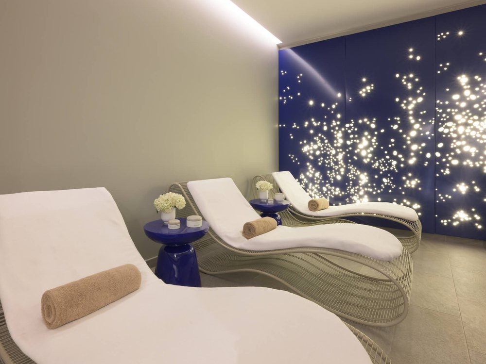 La salle de repos du spa myBlend de L'Hôtel du Golf, des lits de repos blancs devant un mur bleu nuit constellé de lumières