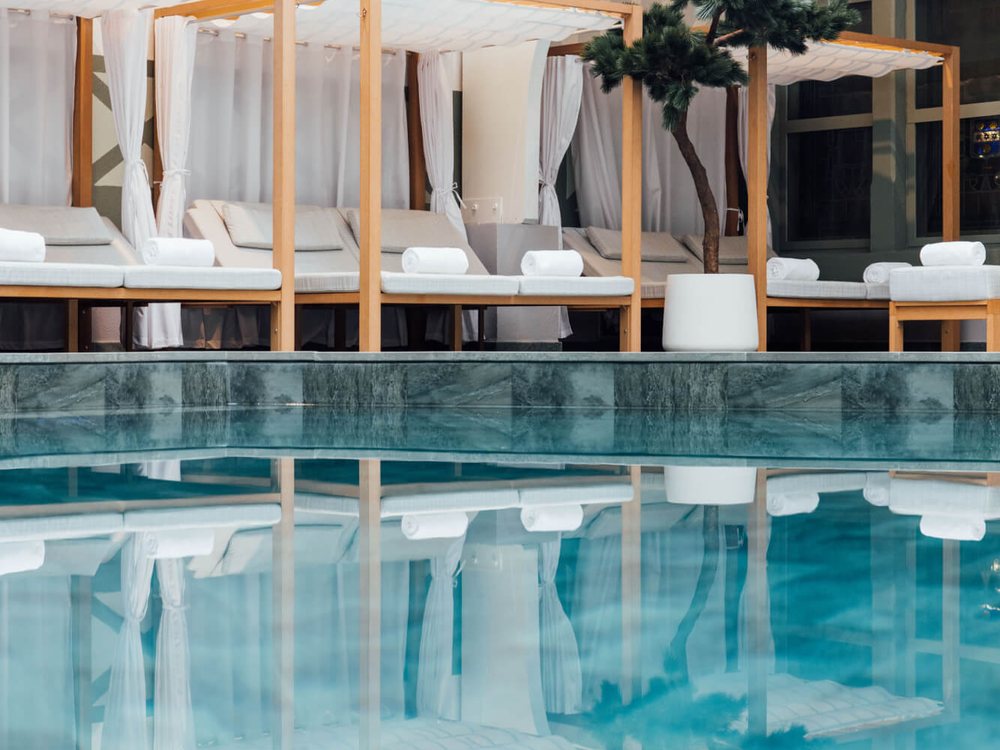 La piscine intérieure du Spa Guerlain du Normandy, ses lits de repos sous des voilages blancs et ses reflets turquoise