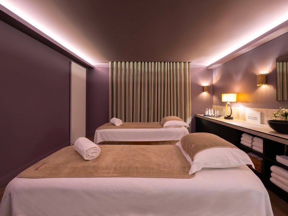 Une cabine de soins en duo du spa du Royal, à Deauville, deux tables sous une lumière rose et des rideaux tissés
