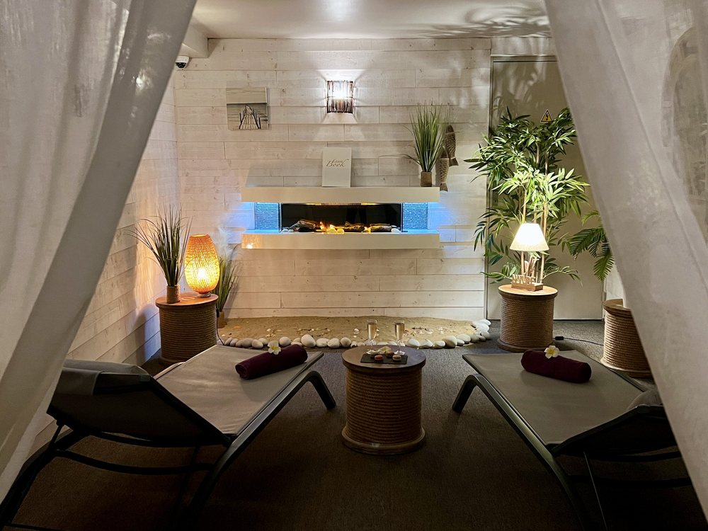 La Suite Esprit de Spa du Trophée, deux lits de repos, une cheminée et des voilages blancs autour d'une lumière douce