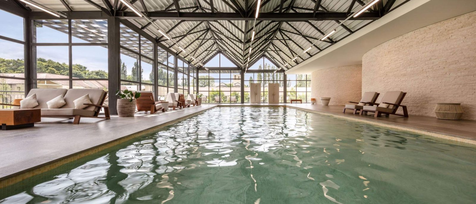 La piscine intérieure du spa du Grand Pavillon Chantilly, sous sa charpente métallique et ses grandes baies vitrées