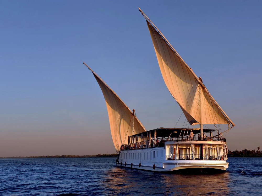 La dahabieh La Flâneuse du Nil toutes voiles dehors sur le fleuve à la lumière dorée du soir