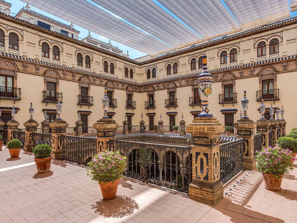 Le patio central de l'Hotel Alfonso XIII, ses arcades, ses azulejos et ses plantes sous un velum
