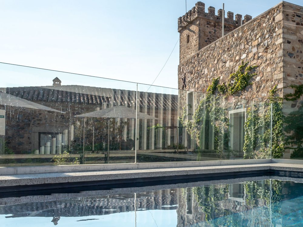 La piscine extérieure d'Atrio, son eau calme au pied d'une tour de pierre de la vieille ville de Cáceres
