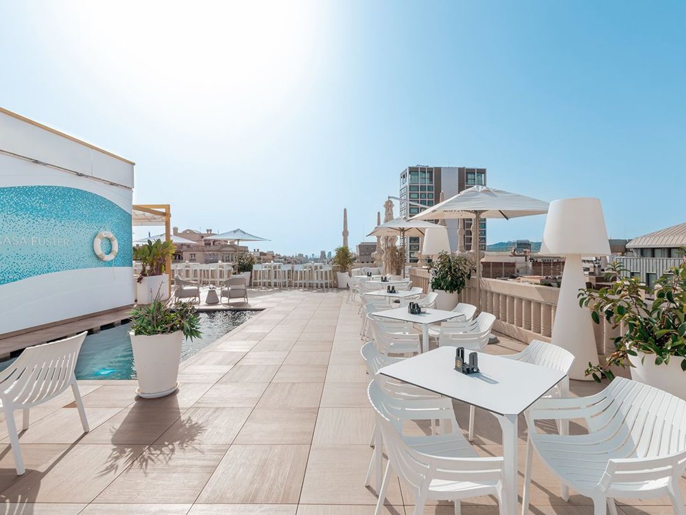 La terrasse sur le toit de l'Hotel Casa Fuster, sa piscine bordée de mosaïque bleue et ses tables blanches