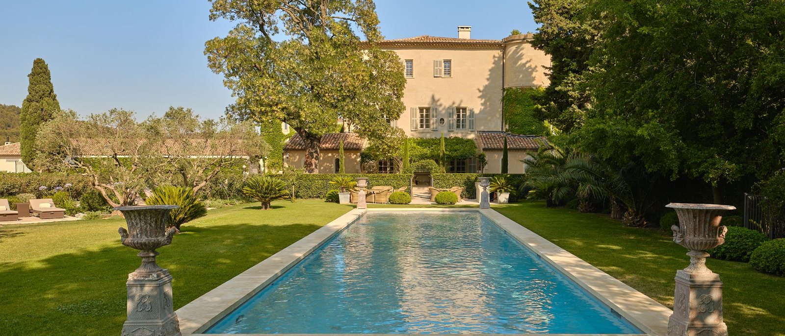 La piscine du Château d'Estoublon sur la pelouse, le château en arrière-plan