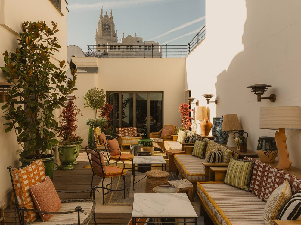 La terrasse sur le toit du Brach Madrid, banquettes, coussins colorés et plantes, un clocher au fond
