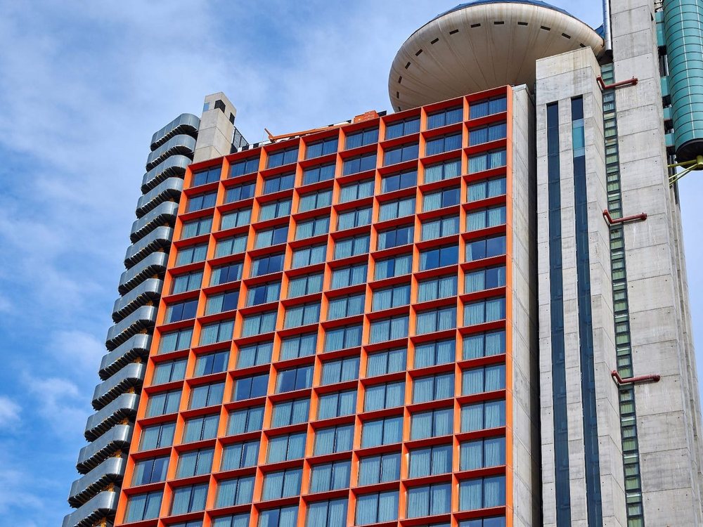 La tour du Hyatt Regency Barcelona Tower, façade rouge et dôme de verre, sous un ciel bleu