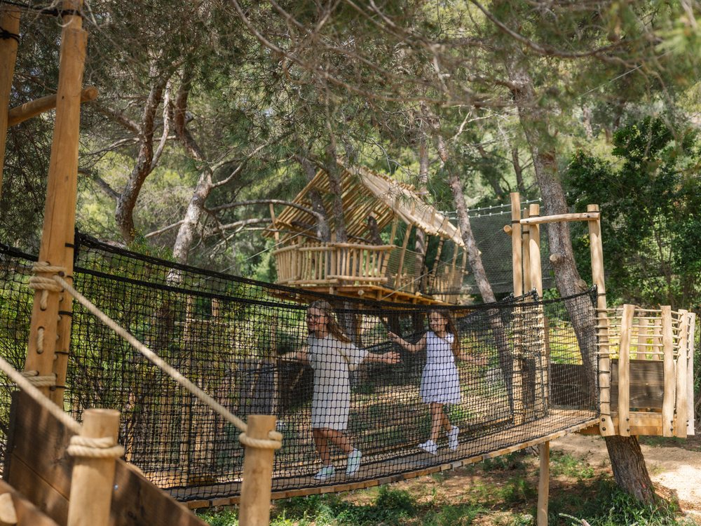 Deux fillettes traversent le pont de filets du Kids Club du Grand-Hôtel du Cap-Ferrat, sous les pins