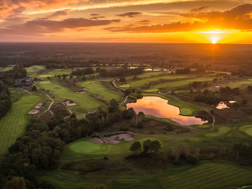 Vue aérienne des parcours de Cabot Bordeaux au coucher du soleil, entre bruyères, pins et plans d'eau