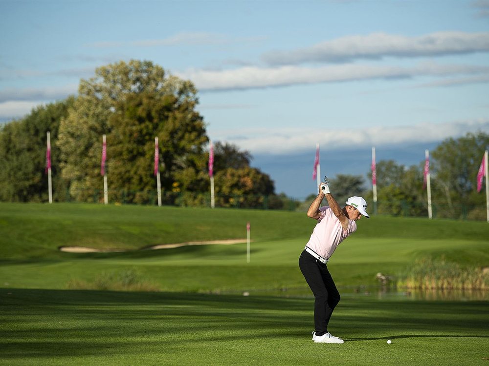Un golfeur en fin de swing sur un départ de l'Evian Resort Golf Club, le lac Léman en arrière-plan